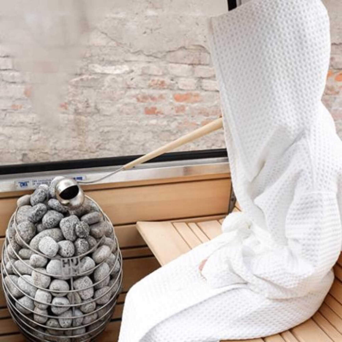 Huum Drop heater in a bright room with a white towel hanging beside it