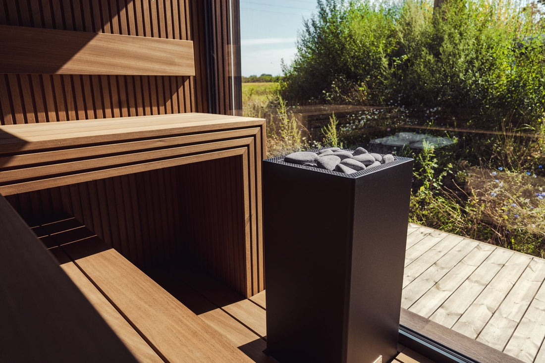 Compact single-person traditional sauna interior with light wood benches and a stone heater