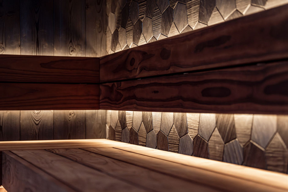 Two-tone sauna interior with a light cedar bench and a darker wood accent wall under LED lighting