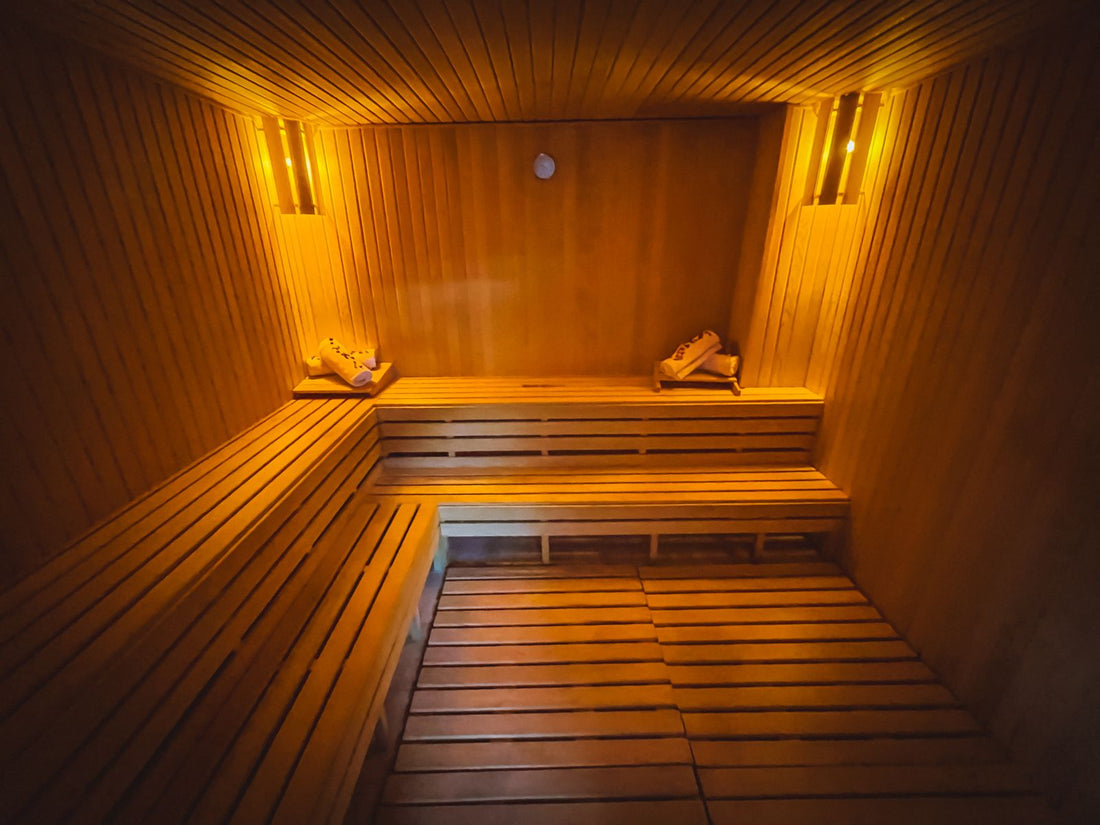 Warm amber-lit wooden home sauna interior with tiered benches, suited to a red light sauna wellness routine