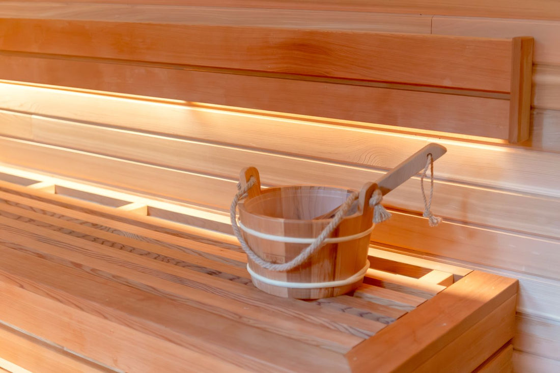 Light cedar home sauna interior with a wooden bucket and ladle on the bench