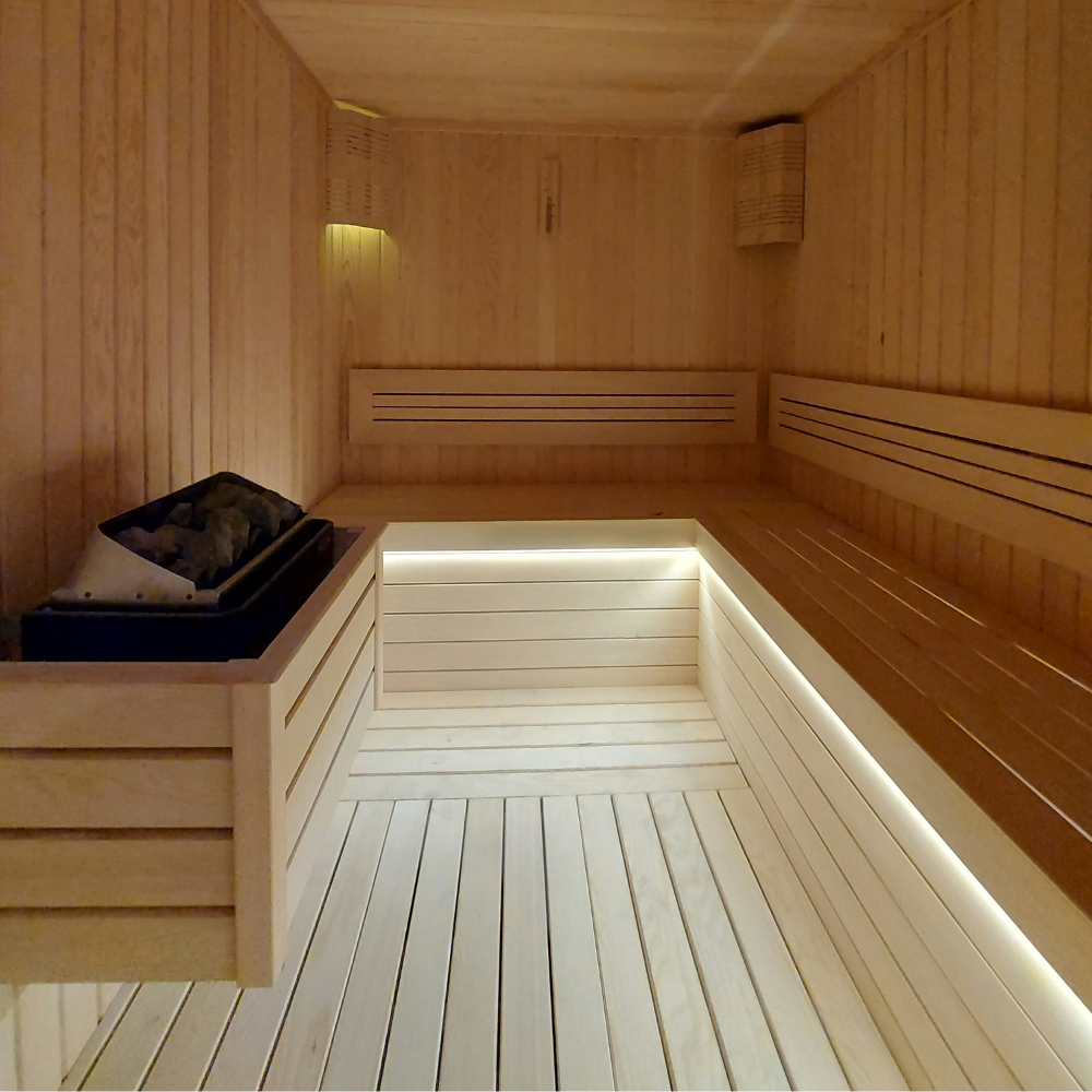 Interior of a cedar home infrared sauna with wood bench seating, a calm space for stress and cortisol relief.