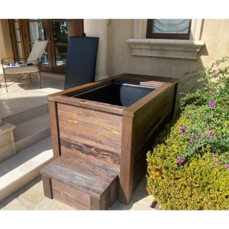 Kooru cold plunge tub with entry step installed beside a garden bed