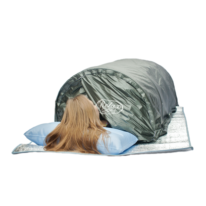 Person lying in the Relax Flex sauna with head resting on a pillow outside the tent