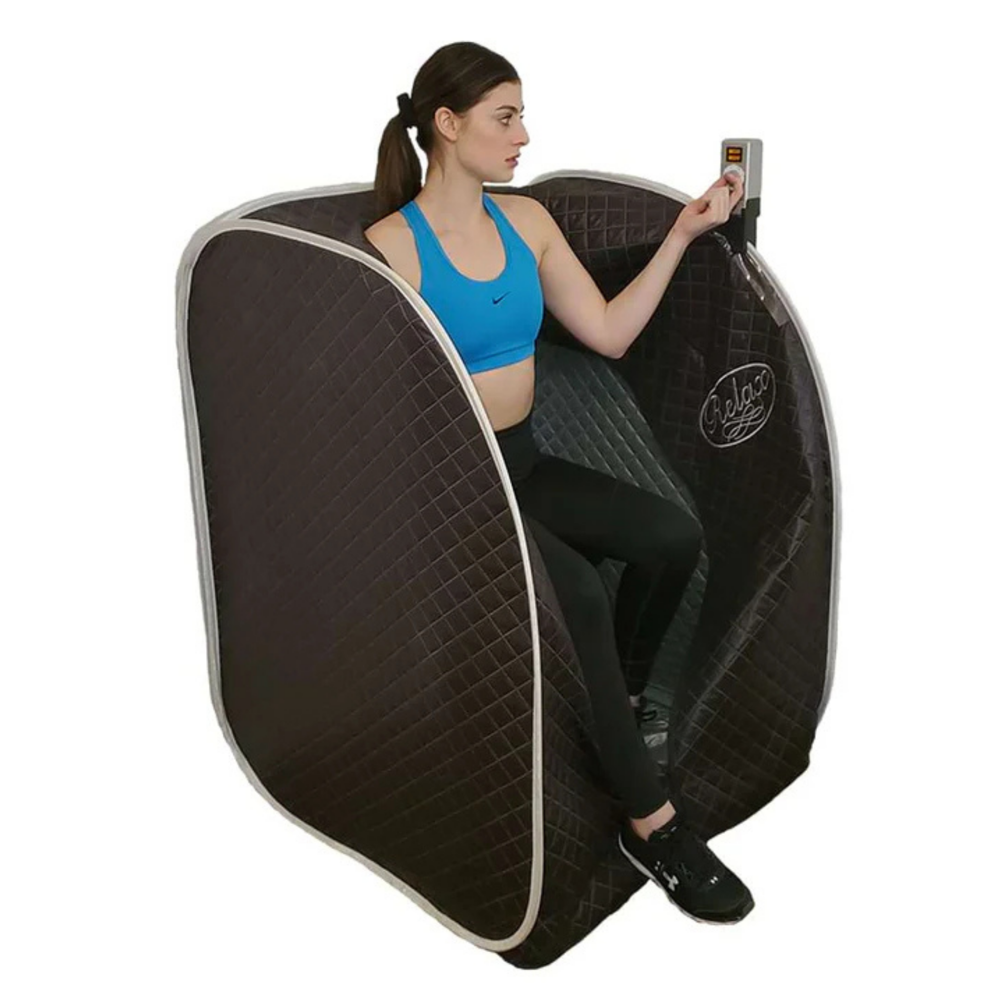 Person seated inside the Relax Black Pro far infrared sauna with the handheld controller