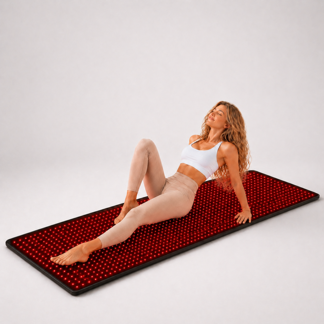 Person reclining on the illuminated iReliev FullGlow 180 red light mat
