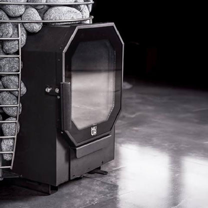 Huum Hive Flow Mini stove with its glass firebox door on a dark polished floor